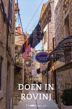 an alleyway in the old town of rovini, croatia with signs hanging from buildings