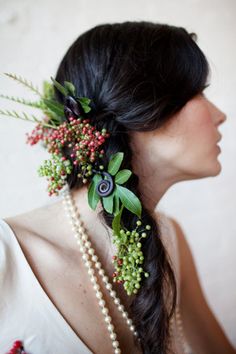 a woman wearing pearls and flowers in her hair