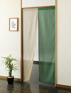 a room divider with a plant in it and pictures on the wall behind it