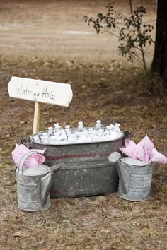 two buckets filled with bottles sitting on the ground next to a sign that says waiting hole