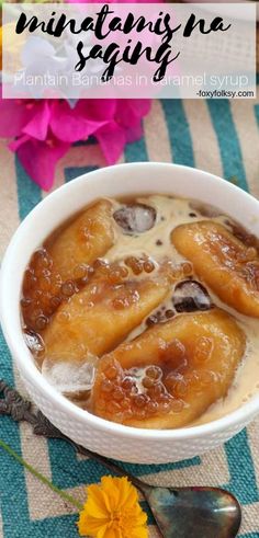 a bowl filled with bananas sitting on top of a blue and white table cloth next to flowers