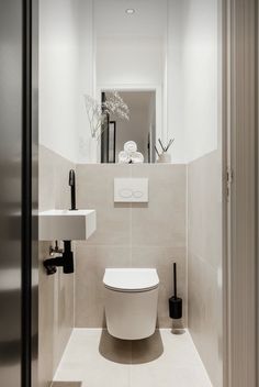 a white toilet sitting next to a sink in a bathroom under a mirror above it