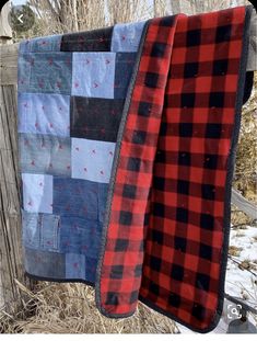 two quilts hanging on a wooden fence in the winter with snow and trees behind them