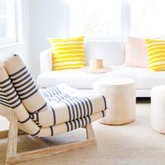 a living room filled with white furniture and striped pillows on top of it's covers