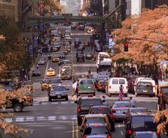 a busy city street filled with lots of traffic and tall buildings on either side of the road