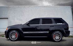 a black suv parked in front of a building with red rims on it's tires