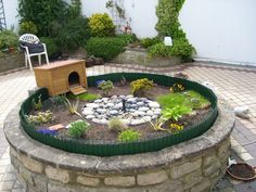 a small garden with rocks and plants in the center, surrounded by brick pavers