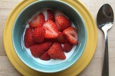 a bowl of strawberries with yogurt and a spoon