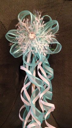 a blue and white flower on top of a black couch with ribbon around it's center