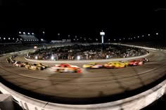 a group of cars driving around a track at night