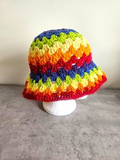 a multicolored crocheted hat sits on a white mannequin head