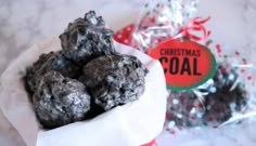 a bowl filled with chocolate covered cookies next to a bag of christmas coals on top of a table