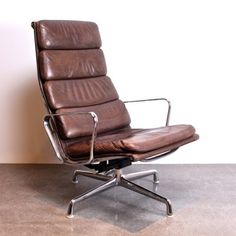 a brown leather office chair sitting on top of a cement floor next to a white wall