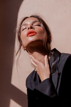 a woman with her eyes closed wearing an orange lipstick