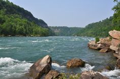 a river with rocks and water running through it, surrounded by green trees in the background