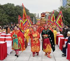 some people are dressed in colorful costumes and standing near tables with red tablecloths