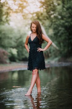 a woman standing in the water with her hands on her hips and looking at the camera