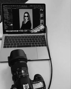 a laptop computer sitting on top of a desk next to a camera and a lens