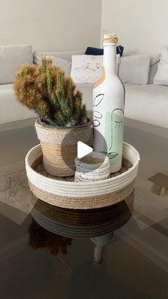 a glass table with a bottle and some plants in it on top of the table