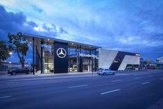 a mercedes dealership at dusk with cars parked outside