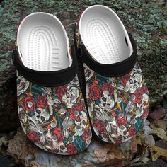 a pair of slippers with skulls and roses on them sitting on some rocks in the woods