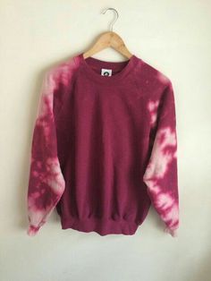 a pink and white tie dye sweater hanging on a wall