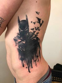 a batman tattoo on the back of a man's stomach, with birds flying around it