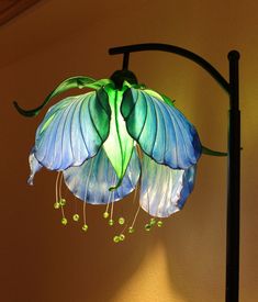 a blue and green flower hanging from a lamp