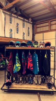 several snowboard jackets and goggles are hanging on a rack in a storage area