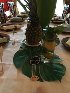 a pineapple centerpiece on top of a table with plates and napkins around it