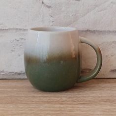 a green and white mug sitting on top of a wooden table