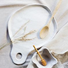 a wooden spoon sitting on top of a white plate next to a bowl with a honey comb in it