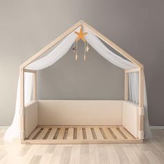 a wooden bed with white drapes and a star hanging from it's side