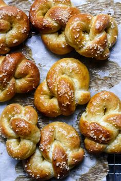 freshly baked pretzels sitting on top of a piece of parchment paper with salt sprinkled on them