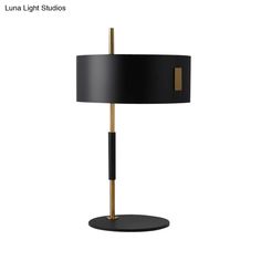 a lamp with a black shade and gold trim on the bottom is shown in front of a white background