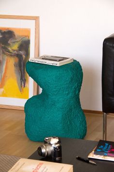 there is a green chair with a book on it and a camera next to it