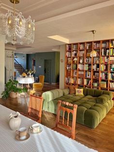 a living room filled with furniture next to a table and bookshelf full of books