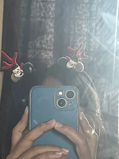 a woman taking a selfie in front of a mirror with christmas decorations on her head