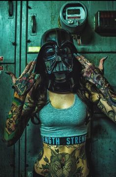 a woman with tattoos on her arms and chest wearing a darth vader mask