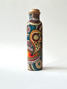 a decorative bottle is sitting on a white surface with an intricate design painted on it