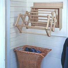 a basket hanging from the side of a wall next to a coat rack and clothes hanger