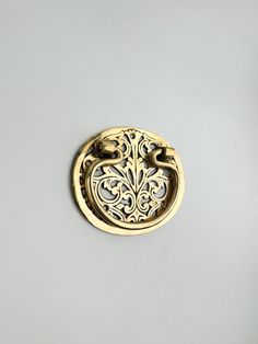 an ornate brass door handle on a white wall with a black cat in the background