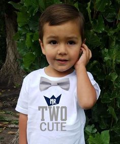 a young boy wearing a t - shirt that says two cute