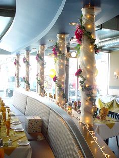 an empty restaurant is decorated with lights and flowers on the walls, along with long banquet tables