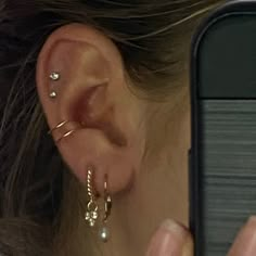 a woman is looking at her cell phone while wearing ear piercings