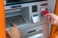 a person is using an atm machine to pay for their credit card or other item