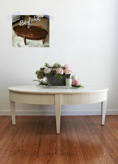 a coffee table with flowers on it in front of a white wall and wooden floor