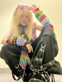 a woman sitting on the ground with her hands in her hair and wearing colorful bracelets