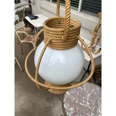 a white light hanging from a ceiling with rope wrapped around it's bottom and sides