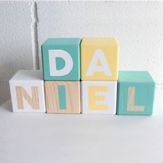 wooden blocks spelling the word dad's name on a white surface with a wall in the background